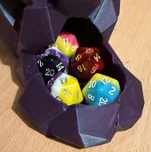A selection of D20s in a 3D printed dice tray - some of the dice have non-binary and pansexual pride flag designs