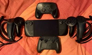 A Steam Deck, surrounded with the Frame controllers, the Index controllers with grips attached, the Steam Controller (2015) and the Steam Controller (2026)