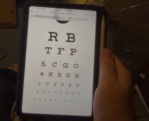 An iPad Mini with an optician's eye chart viewed through the Apple Vision Pro. Most lines are legible, save the bottom one.