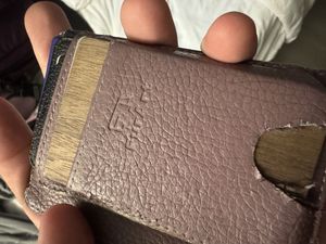 A very scuffed up wallet with a scaly texture, with the word 'FurArt' embossed