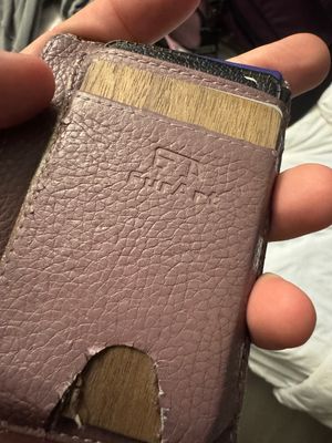 A very scuffed up wallet with a scaly texture, with the word 'FurArt' embossed